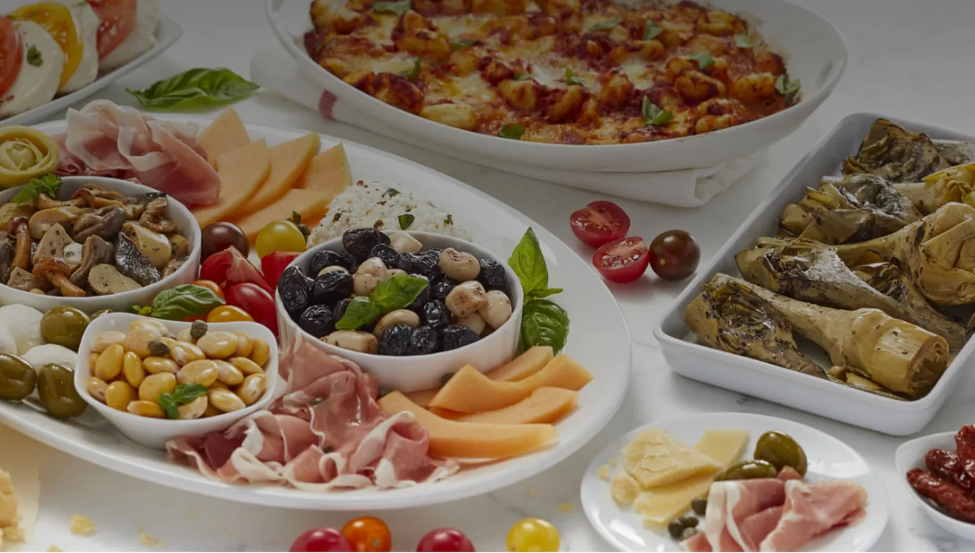 A table of antipasto, pizza and marinated vegetables